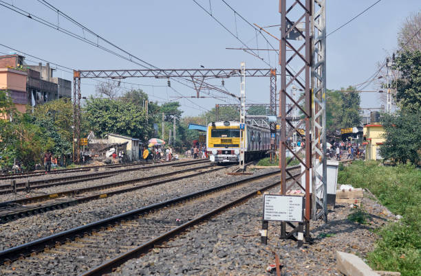 West Bengal, 02/13/2022: An Indian Railway electric locomotive EMU (local train) departing from a crowded suburban station. Mostly connecting Kolkata and its suburban areas, these trains (running through Main lines and Chord lines) are lifelines of Kolkata and district areas with almost 3.5 million daily commuters.
