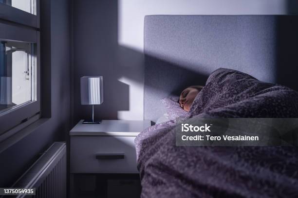 Sleeping Woman In Bed At Night In Dark Bedroom Person Resting Asleep Under Cover And Blanket Cold Room At Home Tired Lady In Peaceful Dream Blue Moonlight From Window Stock Photo - Download Image Now