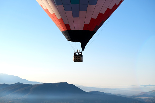 Basket of a hot air balloon flying above the mountains, sunris