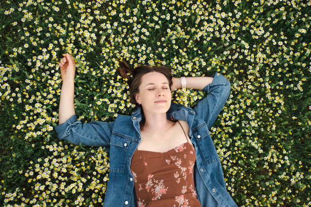 istock Happy woman lying in a green chamomile field 1375062855