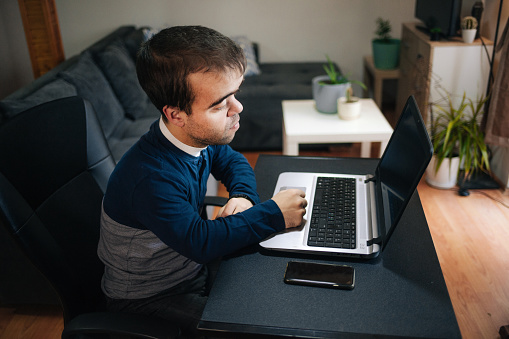 Young man with dwarfism working from home