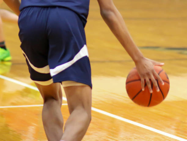 Rear view of basketball player dribbling the ball up court during a game stock photo