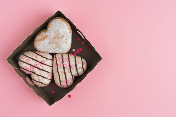 istock Heart-shaped donuts in a box on a pink background. Copy space. 1375063930