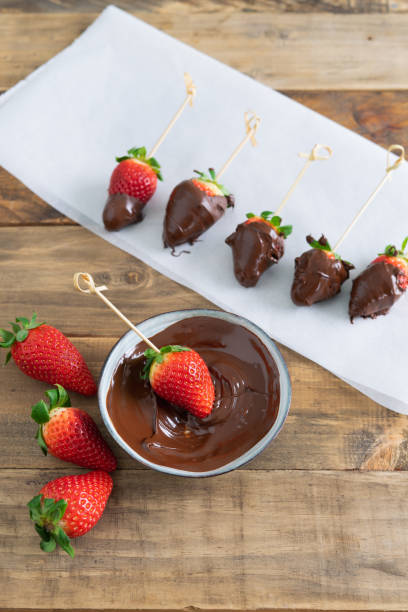 istock Strawberries with chocolate. Strawberries dipping process in chocolate. Copy space. Vertical photo. 1375063931