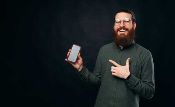 istock Peaceful bearded man is pointing at the phone he is holding in a studio. 1375093198