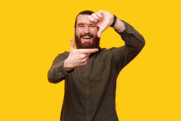 Happy bearded man is making a photo camera frame with his fingers. stock photo