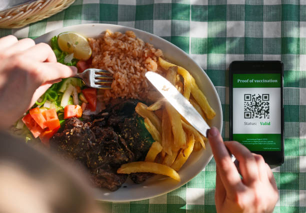 istock Woman in restaurant with certificate of immunization on smartphone. Status is valid. 1375099093