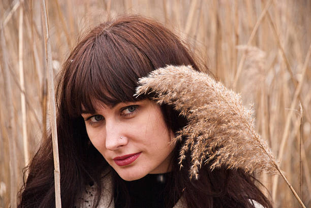 Elegant healthy young brunette woman with fresh clear skin and long dark brown hair outdoors on green grass background, air portrait