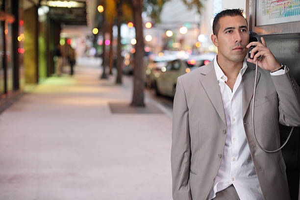 Businessman on a pay phone Image of a Hispanic businessman talking on a pay phone at Downtown Miami pay phone on the phone latin american and hispanic ethnicity talking stock pictures, royalty-free photos & images