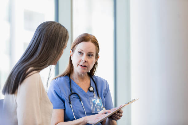 un medico maturo discute i risultati dei test con una paziente di sesso femminile - serious nurse doctor ethnic foto e immagini stock