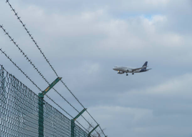 istock Airplane flying over Airport Fence 1375153801