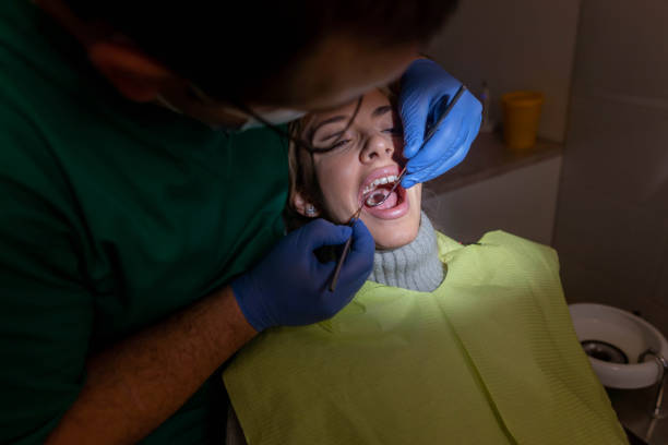 Caucasian male dentist examining the female patient mouth, during monthly control