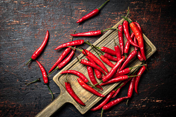 istock Red chili pepper pods on a cutting board. 1375164768