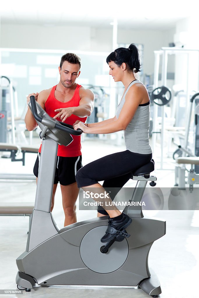 Donna su cyclette con personal trainer - Foto stock royalty-free di 20-24 anni