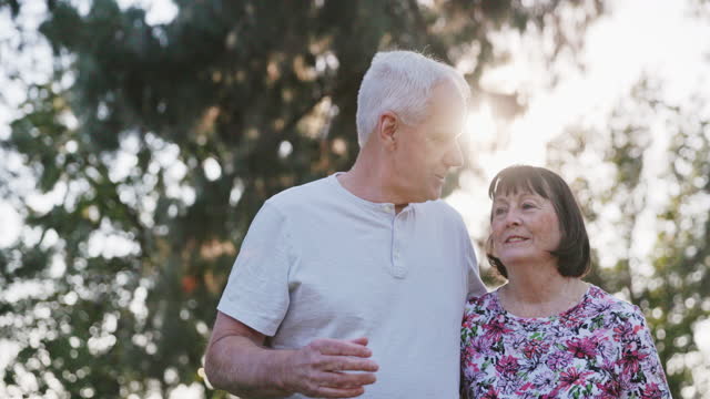 A senior married retired couple enjoying a beautiful sunny evening in the park.