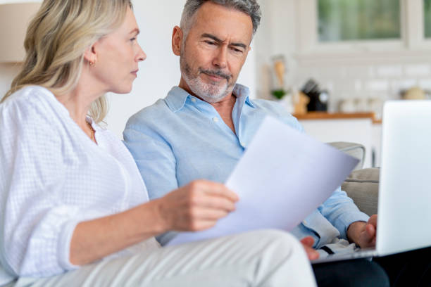 istock Mature couple doing paperwork with a laptop at home. 1375183413