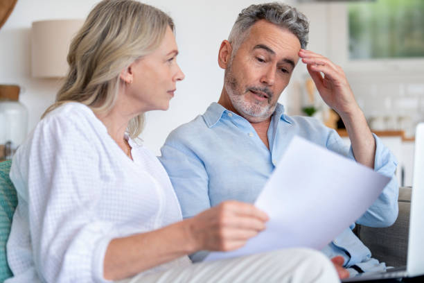 Mature couple doing paperwork with a laptop at home.