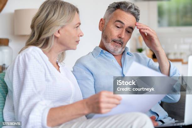 Mature Couple Doing Paperwork With A Laptop At Home Stock Photo - Download Image Now