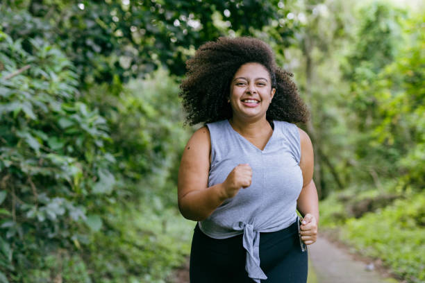 Plus size woman running in the natural park Plus size woman running in the natural park stout stock pictures, royalty-free photos & images