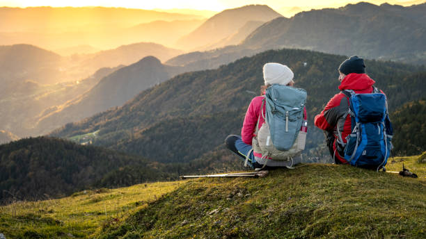 istock Adult pair with backpacks sitting on grass 1375219363
