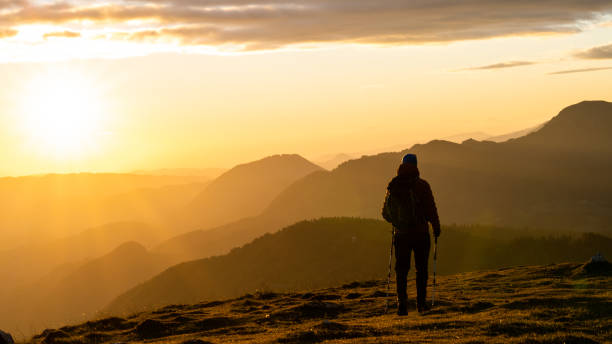 istock Single hiker standing or walking on grass slope in sunset time 1375219375