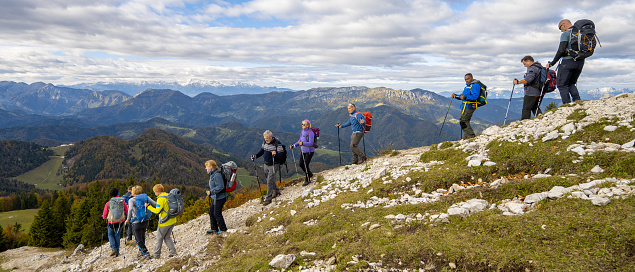 Beautiful view of hiking group walking down on tourist trail. Breath taking panoramic view of ridges and valleys. Hiking in mountains and active lifestyle concept..