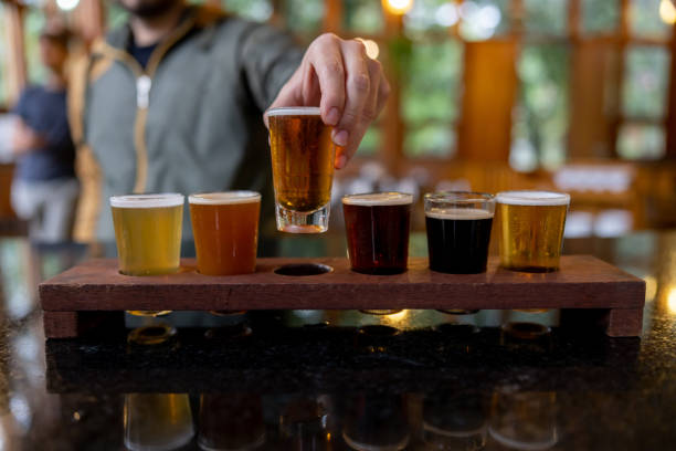 Close-up on a man trying beers from a sampler at a brewery Close-up on a man trying beers from a sampler while taking a tour at a brewery brewery stock pictures, royalty-free photos & images