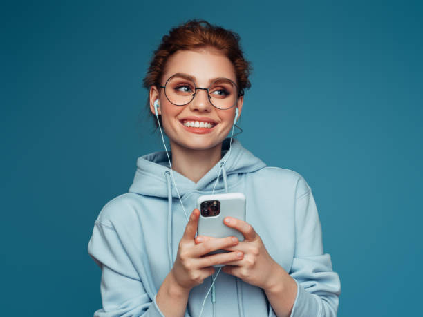 Close-up portrait of a young pretty girl in a blue hoodie using smart phone stock photo