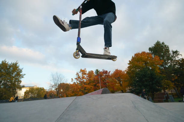 Teenager performs trick in the city skate  park. Push scooter. He is jumping. Extreme sports is popular among youth. View of park of body