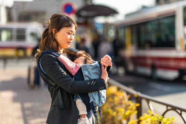 Working mother commuting with her small baby while using smart watch in the city