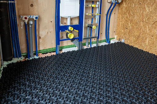 Overall shot of heating pipes laid into grid under future floor. Wooden building interior. Construction of modern family house.