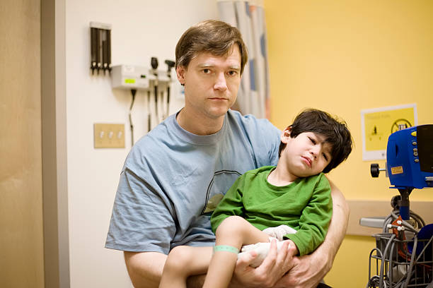 Worried father holding his sick disabled son in hospital stock photo