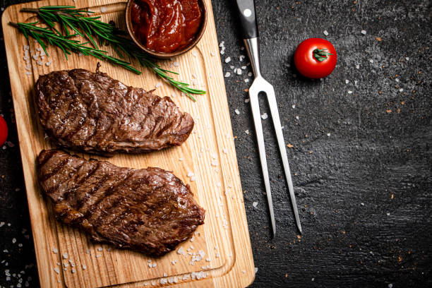 istock Grilled steak with tomato sauce and rosemary on a cutting board. 1375278231