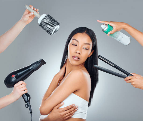 foto de estudio de una atractiva joven rodeada de productos de peluquería sobre un fondo gris - hair care hairbrush hair dryer human hair fotografías e imágenes de stock