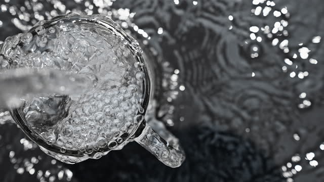 Pouring water into glass at slow motion.