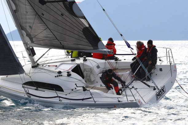 segelboote segeln bei windigem wetter im blauen wasser der ägäis - sailboat storm teamwork competition stock-fotos und bilder