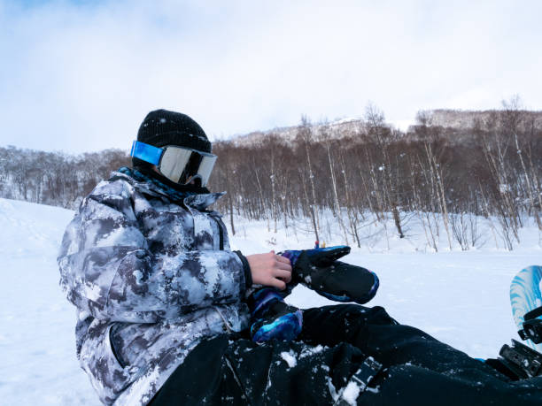 Teenage girl putting on gloves to start snowboarding Teenage girl visiting Hokkaido in winter and enjoying snowboarding. japanese snowboarder stock pictures, royalty-free photos & images