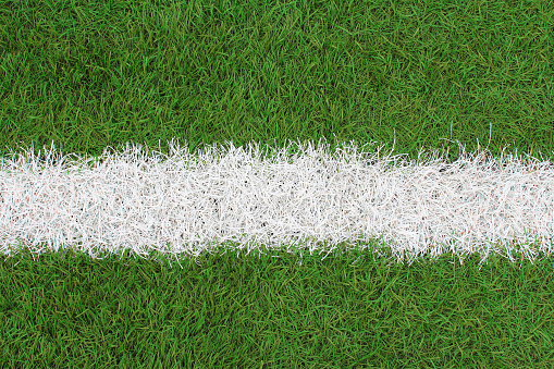Artificial green and white grass on the football field. Top view. Close-up. Background. Texture.