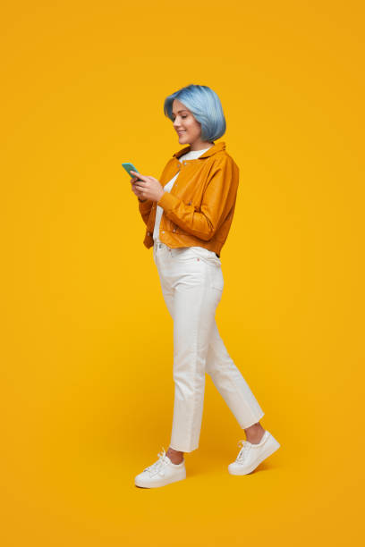 Trendy woman browsing smartphone in studio