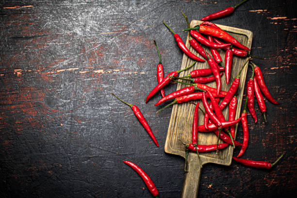 istock Red chili pepper pods on a cutting board. 1375442892