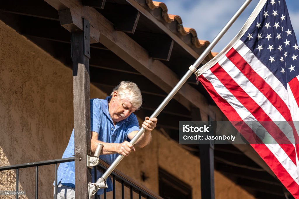 Senior Veteran Hanging Flag High quality stock photo of a senior veteran hanging an American flag outside his home. American Culture Stock Photo