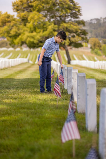 istock Young Boy Placing Flags on Veterans Grave 1375449326