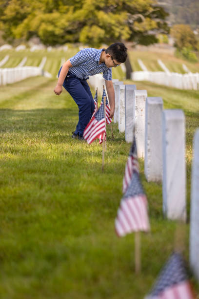 istock Young Boy Placing Flags on Veterans Grave 1375449841
