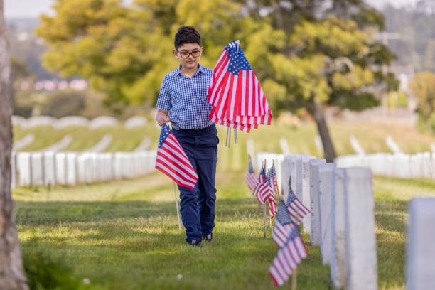 istock Young Boy Placing Flags on Veterans Grave 1375449842