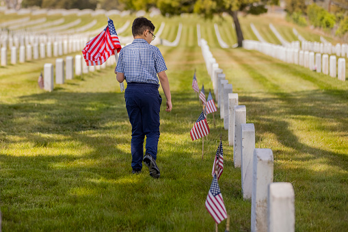 Young Boy Placing Flags on Veterans Grave