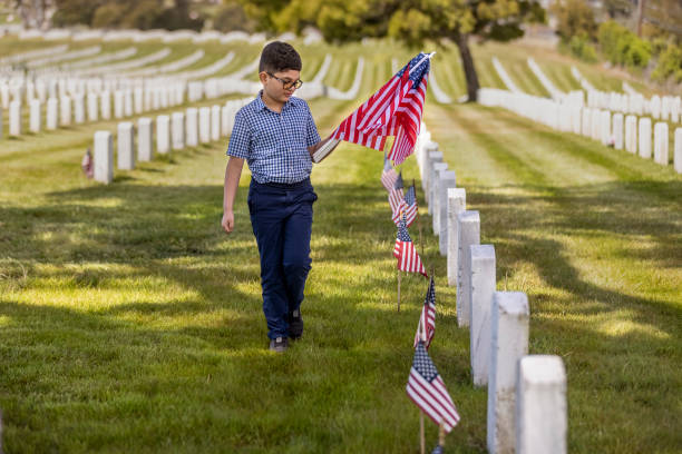 istock Young Boy Placing Flags on Veterans Grave 1375449848