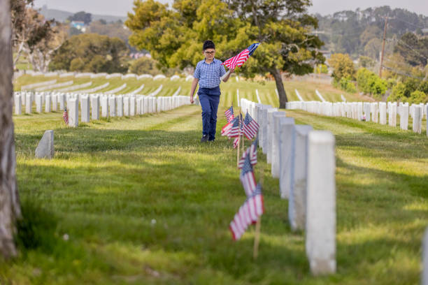istock Young Boy Placing Flags on Veterans Grave 1375450382