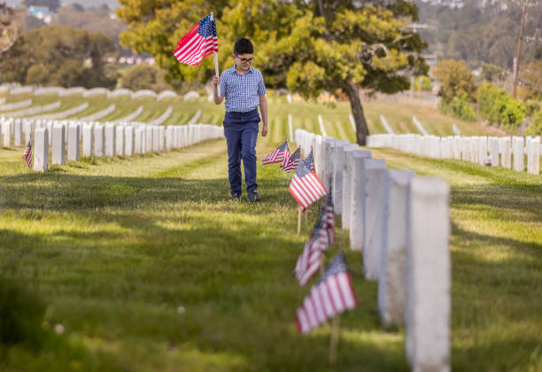 istock Young Boy Placing Flags on Veterans Grave 1375450902