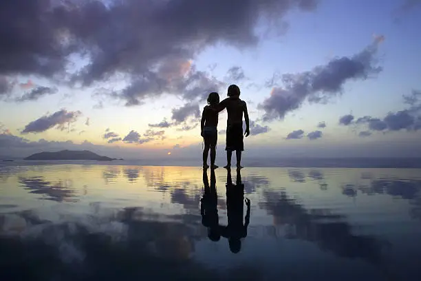 Photo of Children standing on beach at sunset