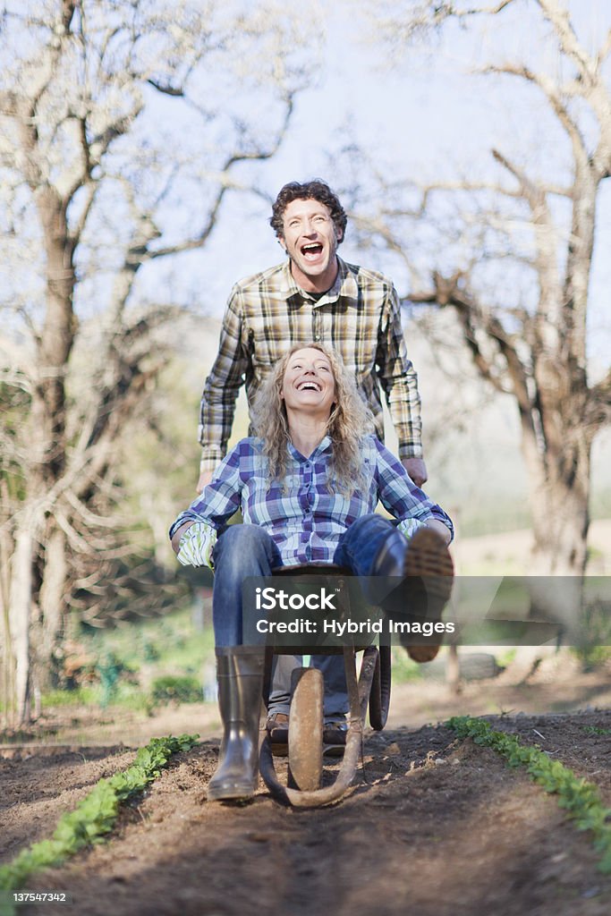 Man pushing girlfriend in wheelbarrow  Riding Stock Photo